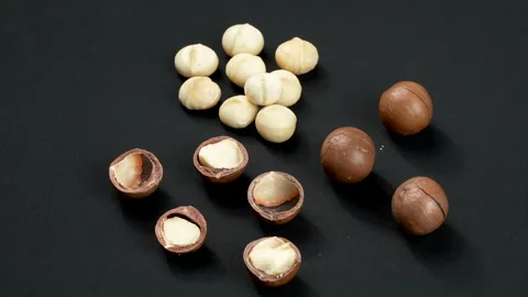 Rotating Assortment of Macadamia Nuts Whole and Cracked on Black. 스톡 동영상 332833605