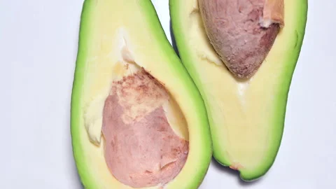 Rotating avocado cut in half on white background Stock Footage 141221749