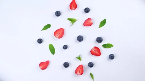A rotating background of blueberries, strawberries, and mint leaves on a white Stock Footage 201293473
