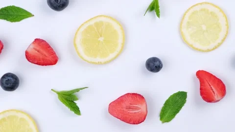 A rotating background of blueberries, strawberries, lemon slices and mint leaves Stock Footage 195036829