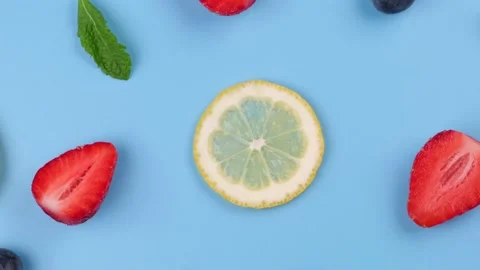 A rotating background of blueberries, strawberries, lemon slices and mint leaves Stock Footage 195086315