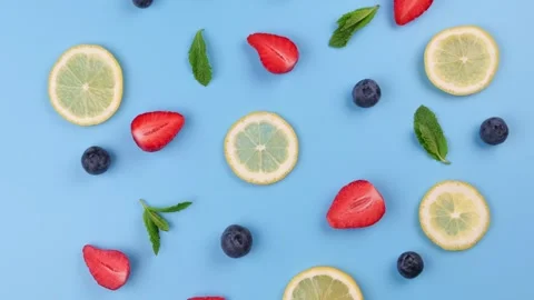 A rotating background of blueberries, strawberries, lemon slices and mint leaves Stock Footage 288488943