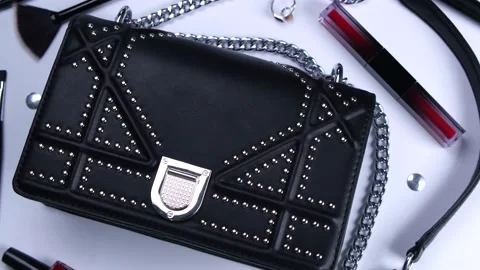 Rotating background with trendy black handbag and decorative cosmetics, nail Stock Footage 211130580