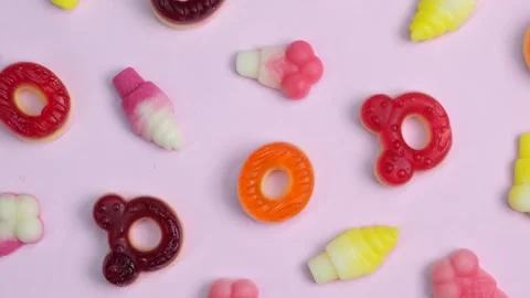 Rotating background of various jelly sweets, bears, donuts, candies, on pink Stock Footage 245618409