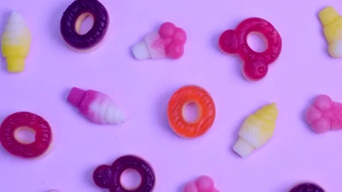 Rotating background of various jelly sweets, bears, donuts, candies, on pink Stock Footage 246575580