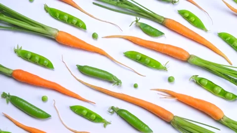 Rotating background of young carrots and green peas on a white background, fresh Stock Footage 198307476