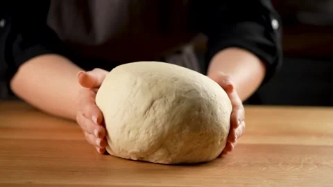Rotating a ball of fresh bread dough with a female hands in slow motion 4K Stock Footage 266220059
