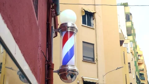 Rotating barber pole mounted on wall of urban building Stock Footage 327164269