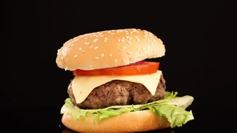 Rotating Beef Burger with Cheese and Vegetables on Black Stock Footage 313270094