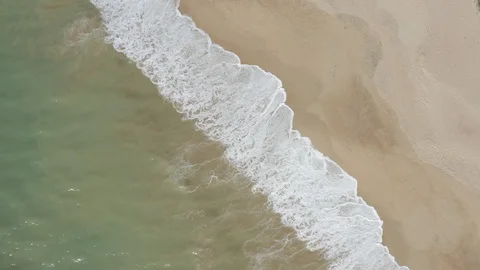 Rotating Birds Eye View Of Waves Hitting The Sandy Shore Stock Footage 128846631