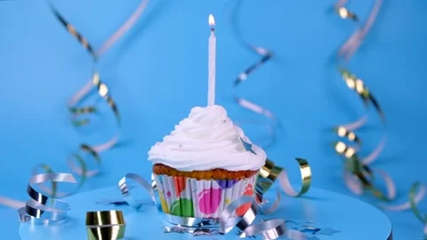 Rotating birthday cake for a boy or man or a cupcake with a burning candle on a Stock Footage 246997526