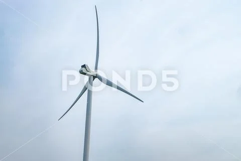 Rotating blades of a windmill propeller on blue sky background. Wind power ge Stock Photos