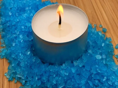 Rotating blue bath salts and a white candle with a flame on wooden background Stock-Footage 77138478