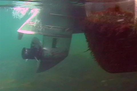 Rotating boat motor propeller moves through crystal clear water Underwater Stock Footage 142398