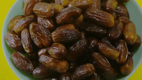 Rotating bowl of dried organic dates on yellow background Video stock 334137232