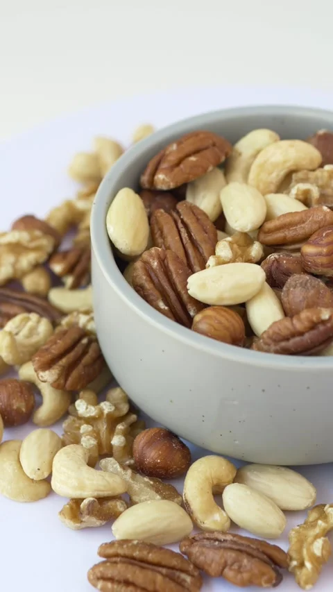 Rotating bowl filled with almonds, hazelnuts, pecans, walnuts, cashews reveals 库存影片 345651937