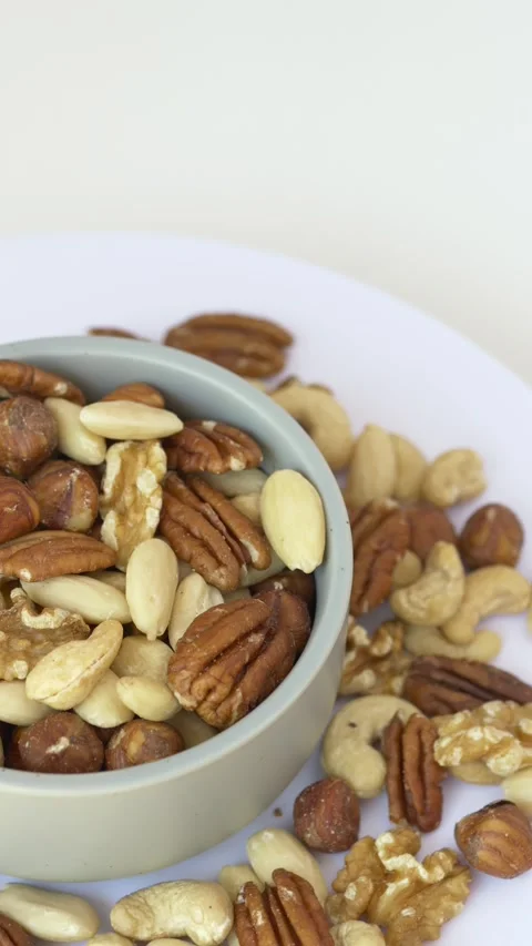 Rotating bowl of mixed nuts viewed from above. Assorted nuts represent healthy Stock Footage 345654239