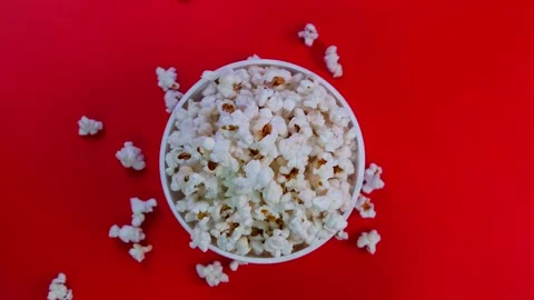 Rotating bucket,box or bowl with popcorn on a red background, the concept of a Stock Footage 196325201