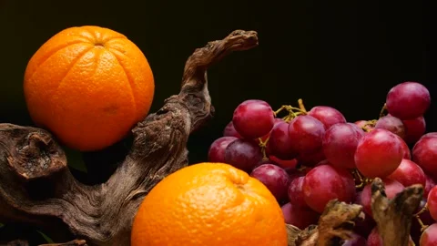 Rotating bunch of red grapes and oranges against a black background. Stock Footage 335212189