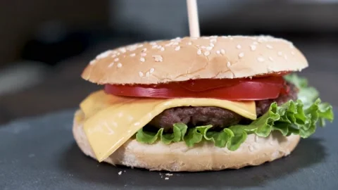 Rotating burger with beef, cheese, tomato, salad leaf in white bun, close-up. Stock Footage 139873715