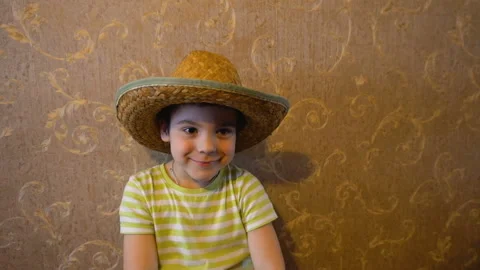 Rotating the camera around the boy in the straw hat against the wall Stock-Footage 106740770