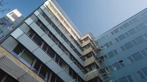 Rotating camera movement in front of modern office building windows reflecting Stock Footage 122212206