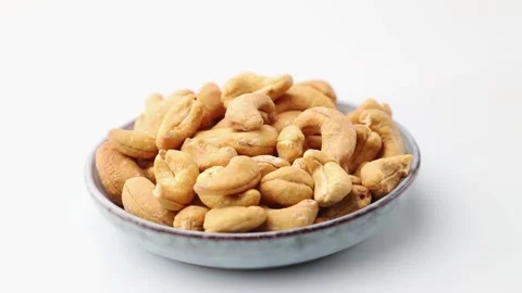 Rotating of cashew in ceramic plate on white background. Side view. Stock Footage 136050428
