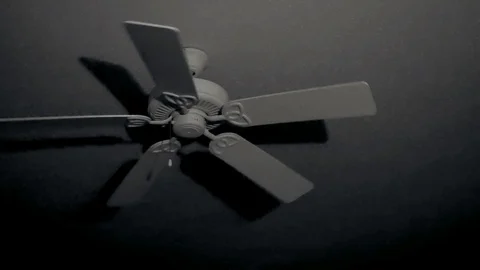 Rotating ceiling fan gradually slows down in dark room at night with shadows. Stock Footage 105200748