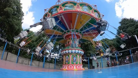 A rotating chair swing ride carousel with teenagers enjoying the ride in a pa Stock Footage 96014792