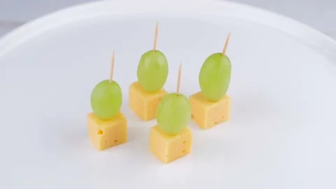 Rotating cheese and grape canapes on white plate or background closeup,snack Stock Footage 194650792