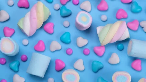 Rotating chewing marshmallows, candies, dragees and sweets on a blue background Stock Footage 204778157