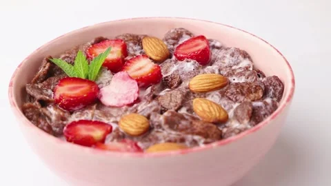 Rotating of chocolate cornflakes with milk and strawberry. Side view, close up. Stock Footage 135042753