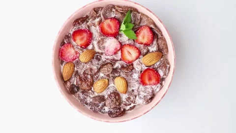 Rotating of chocolate cornflakes with milk and strawberry. Top view, close up. Stock Footage 135042847