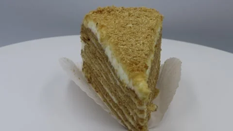 Rotating close-up of a triangular slice of layered cake with creamy filling. Stock Footage 299091711