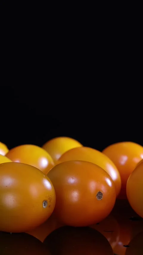 Rotating Close-Up of Yellow Cherry Tomatoes on Black Background Stock Footage 313786929