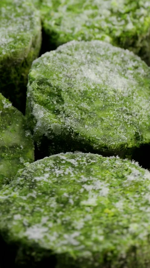 Rotating closeup of frozen spinach cubes with visible ice crystals and textured Stock Footage 310786076