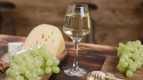 Rotating composition of cheese served with a glass of wine and grapes Stock Footage 105367621