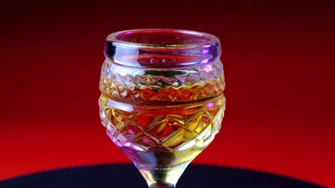 Rotating crystal glass with a drink and flashes of light Stock Footage 218317984