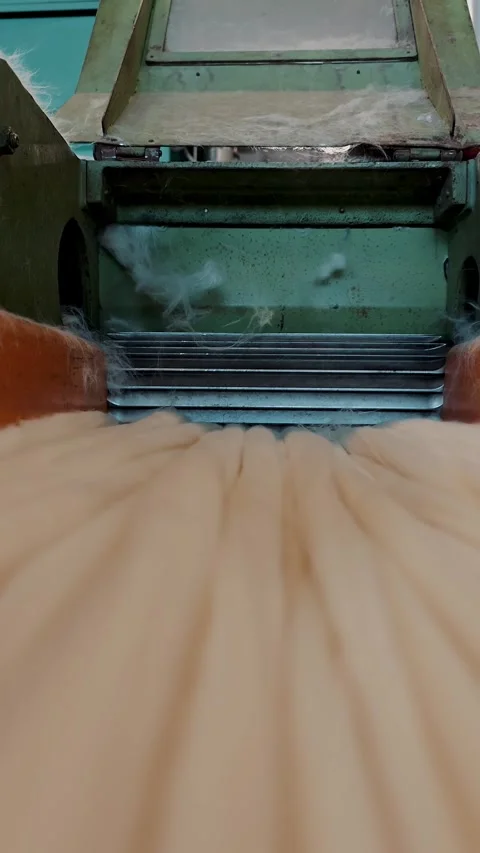 Rotating cutter blades drawing wool fibers into industrial machine Stock Footage 346187827