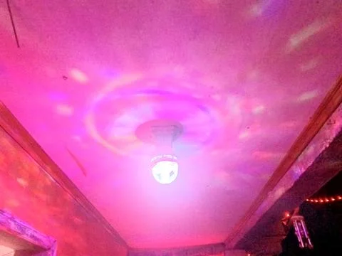 Rotating disco light shines red, blue, and purple on the ceiling. Stock Photos