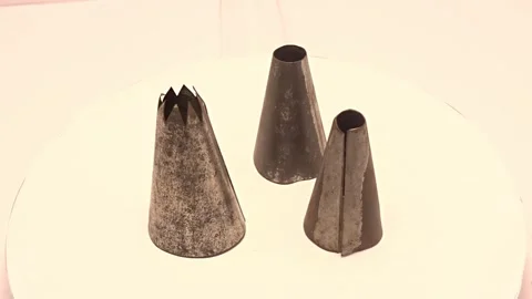 Rotating display of three vintage metal piping tips — 20‑second video Stock Footage 337727785