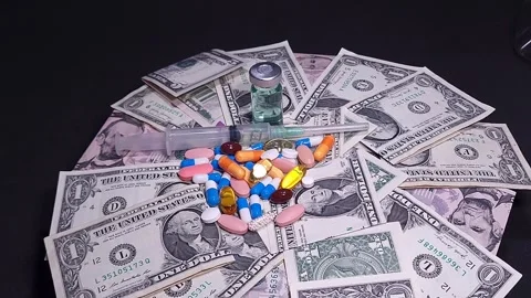 Rotating dollar bills with pills, a syringe, and a vaccine bottle in the cent Stock Footage 318557488