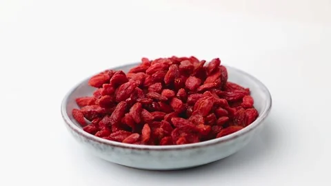 Rotating of dried goji berries in ceramic plate on white background. Side view. Stock Footage 136050338