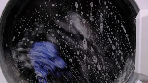 The rotating drum of the washing machine. Washing clothes. Water and foam. Stock Footage 154610200