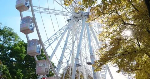 Rotating Ferris wheel and carousel at the Magdeburg city park and downtown Stock Footage 142587566