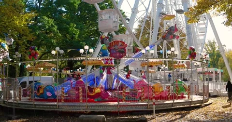 Rotating Ferris wheel, carousel at the city park and downtown at golden Autumn Stock Footage 142589970
