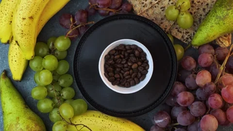 Rotating flatlay of coffee beans on plate with grapes bananas pears and cra.. Stock Footage 320029357