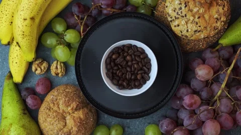 Rotating flatlay of coffee beans on plate with grapes bananas and pears Stock Footage 320029505