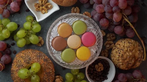 Rotating flatlay of colorful macarons on glass plate with red grapes buns c.. Stock Footage 319967153