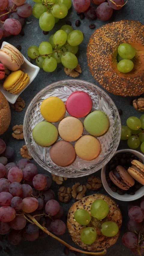 Rotating flatlay of macarons with red and green grapes buns beans and walnuts Stock Footage 319967268
